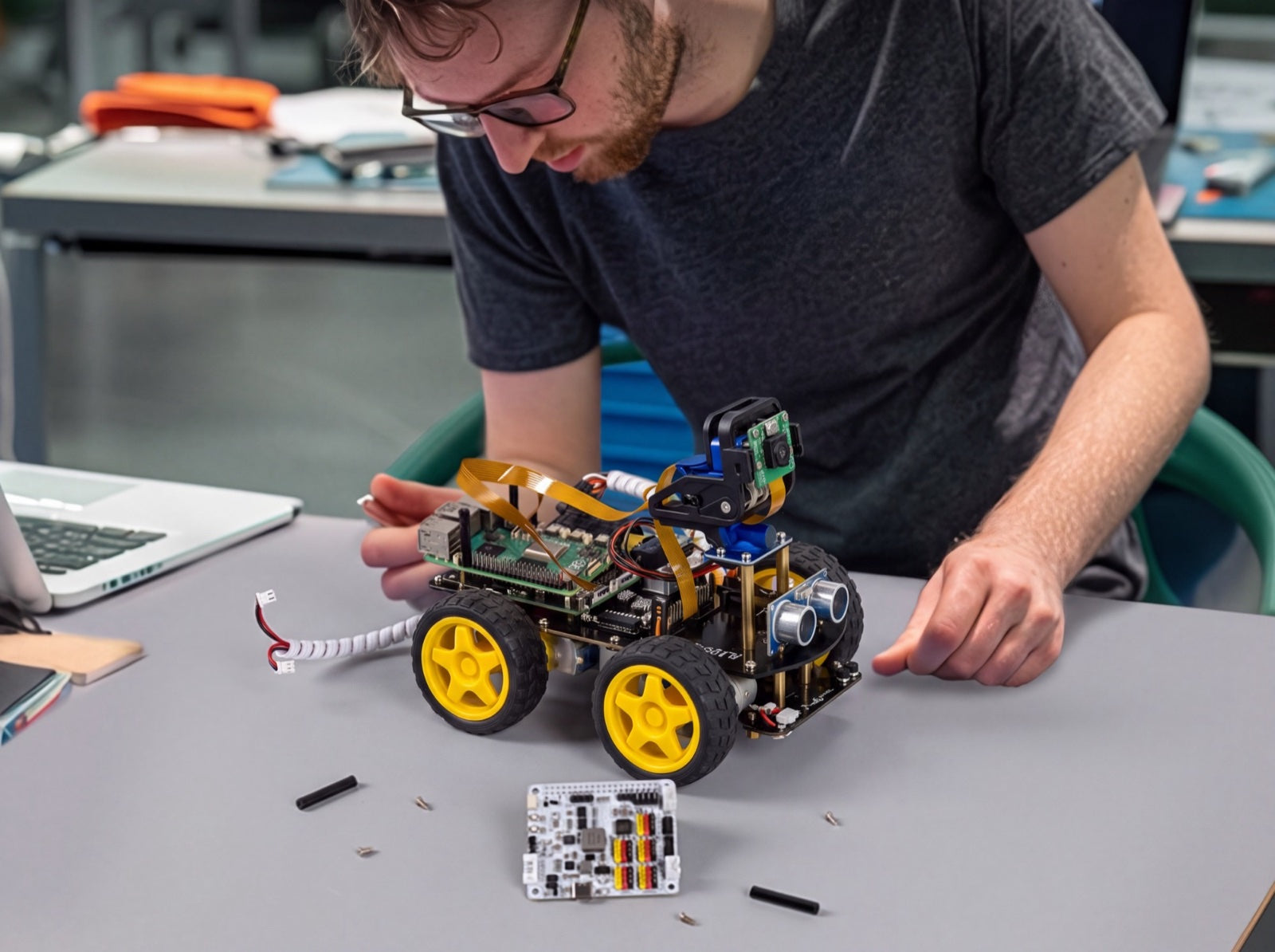 Een maker plaatst de Raspberry Pi op het chassis van de robot
